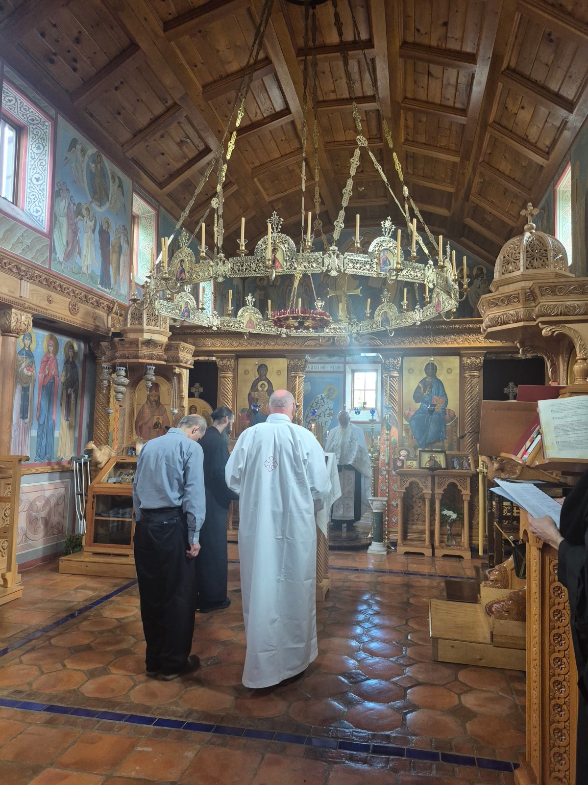 The interior of the parish church: a brass chandelier hanging beneath a vaulted wooden ceiling before the painted iconostasis