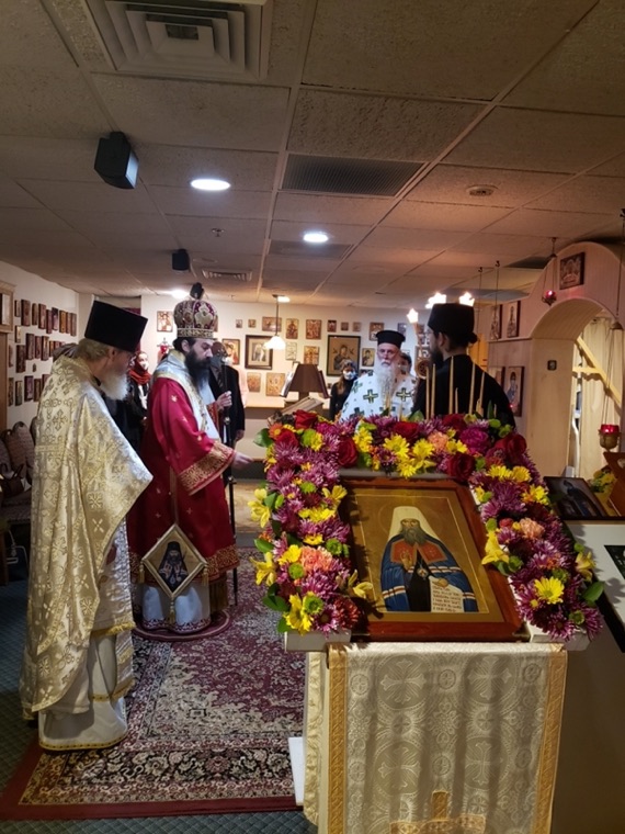 The bishop and clergy standing before the flower-wreathed icon of Saint Philaret during the service