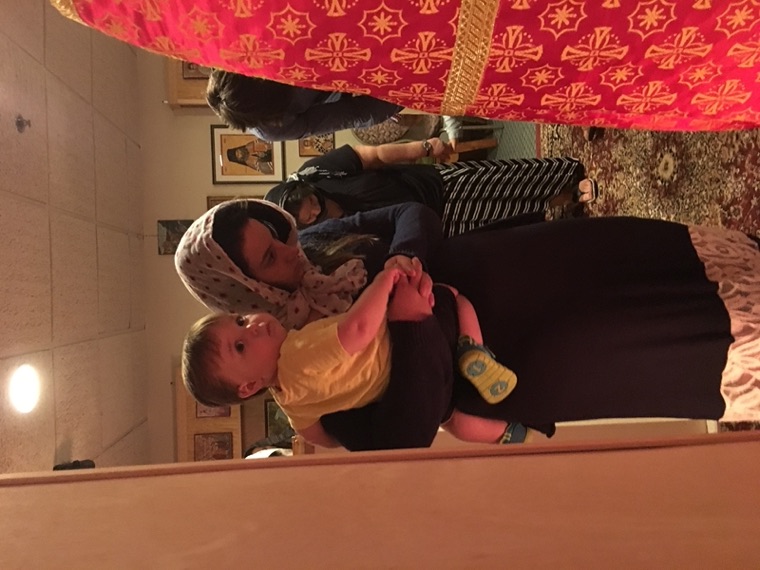 A mother in a headscarf holding her baby during the service